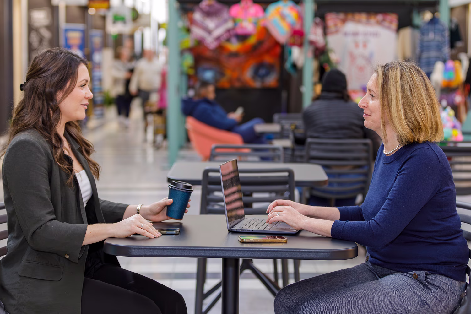 Two women in business attire discussing workflow automation and AI solutions.